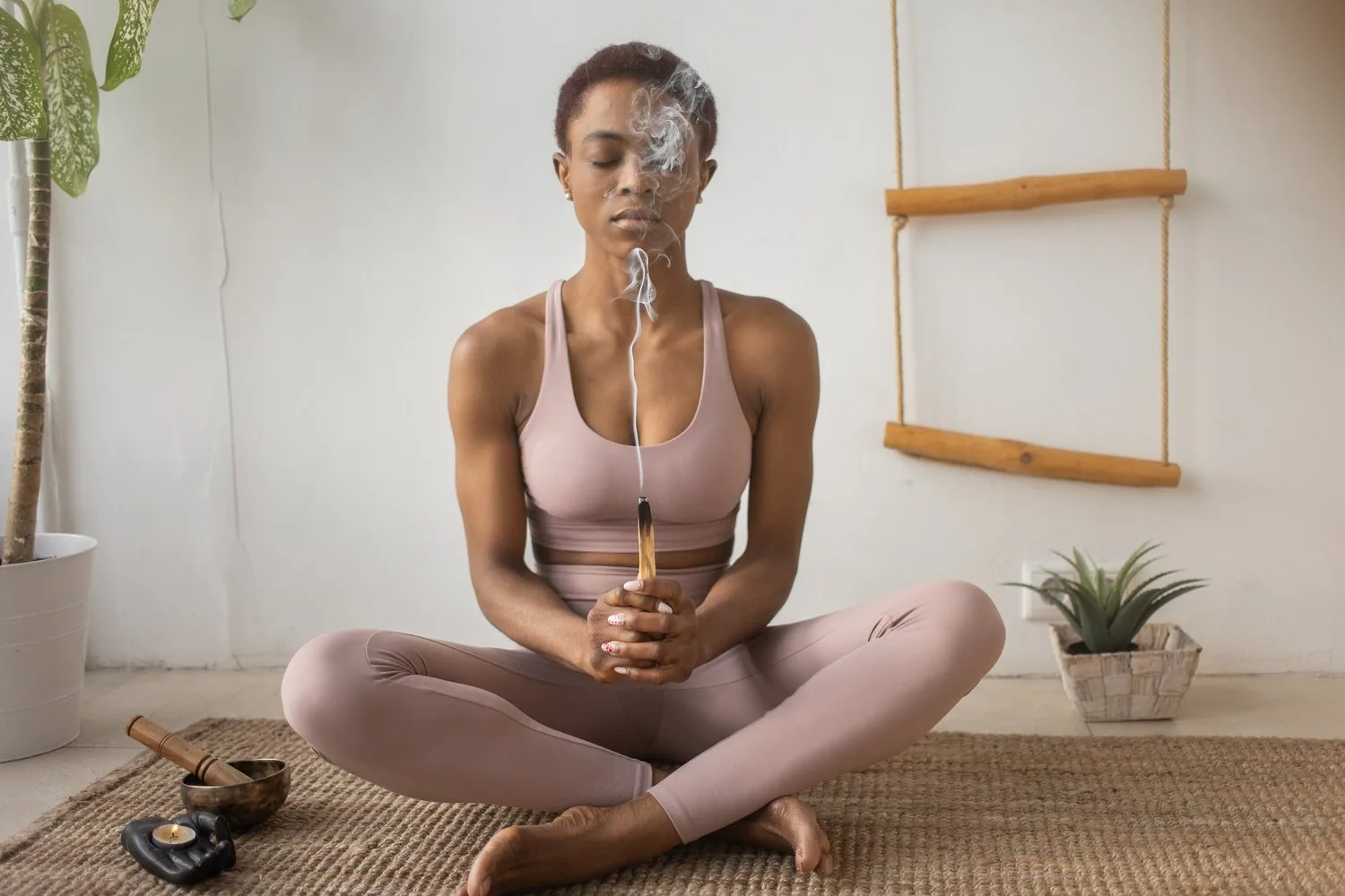 Woman seated cross-legged on the floor with hands at her heart, eyes closed