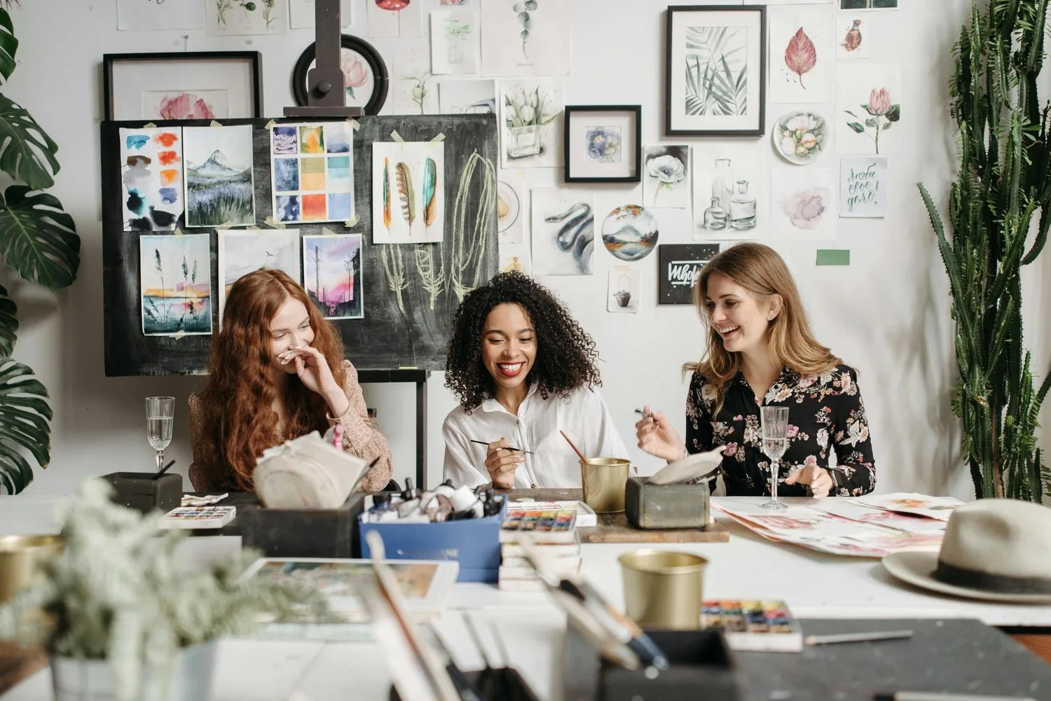 Three coworkers at a cluttered desk looking at a laptop together