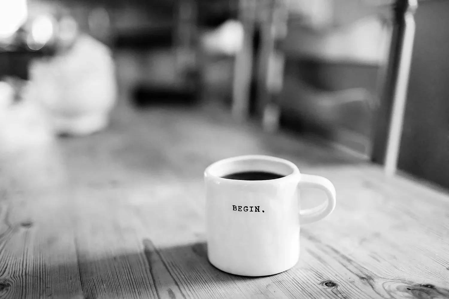 Black-and-white photo of a coffee mug on a wooden table