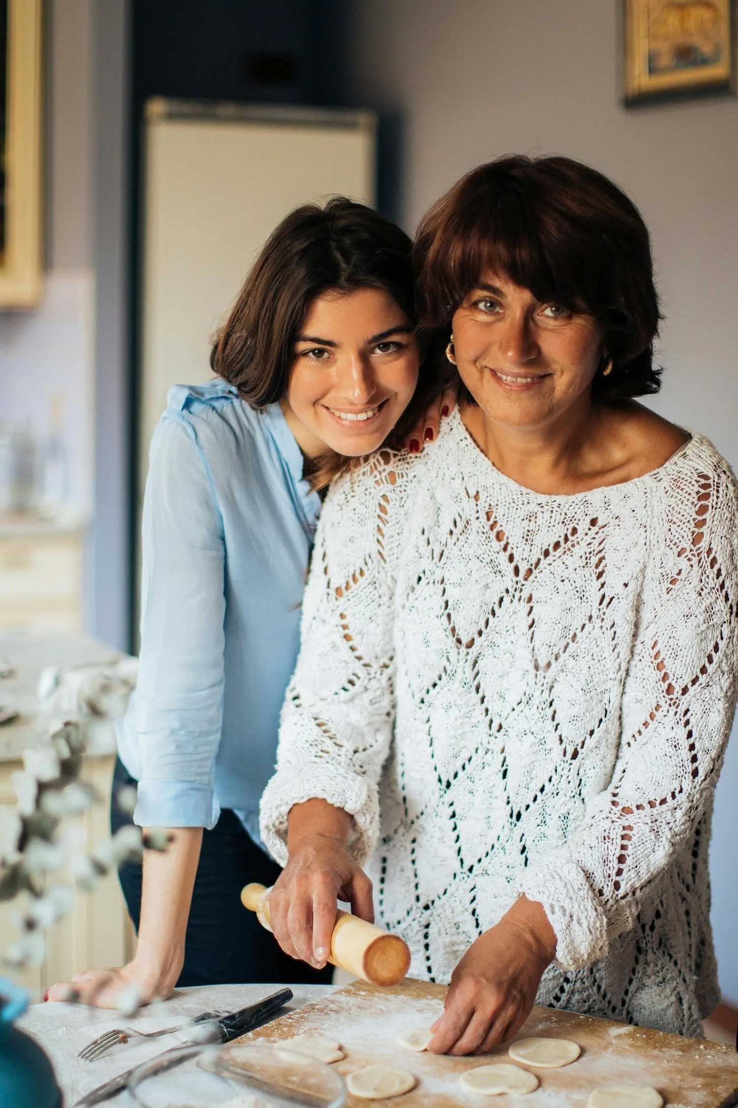 Two women smiling while cooking together in a kitchen