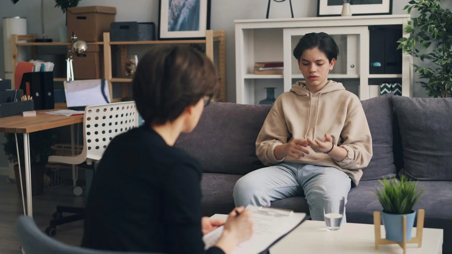 Therapist taking notes while listening to a client in a bright office