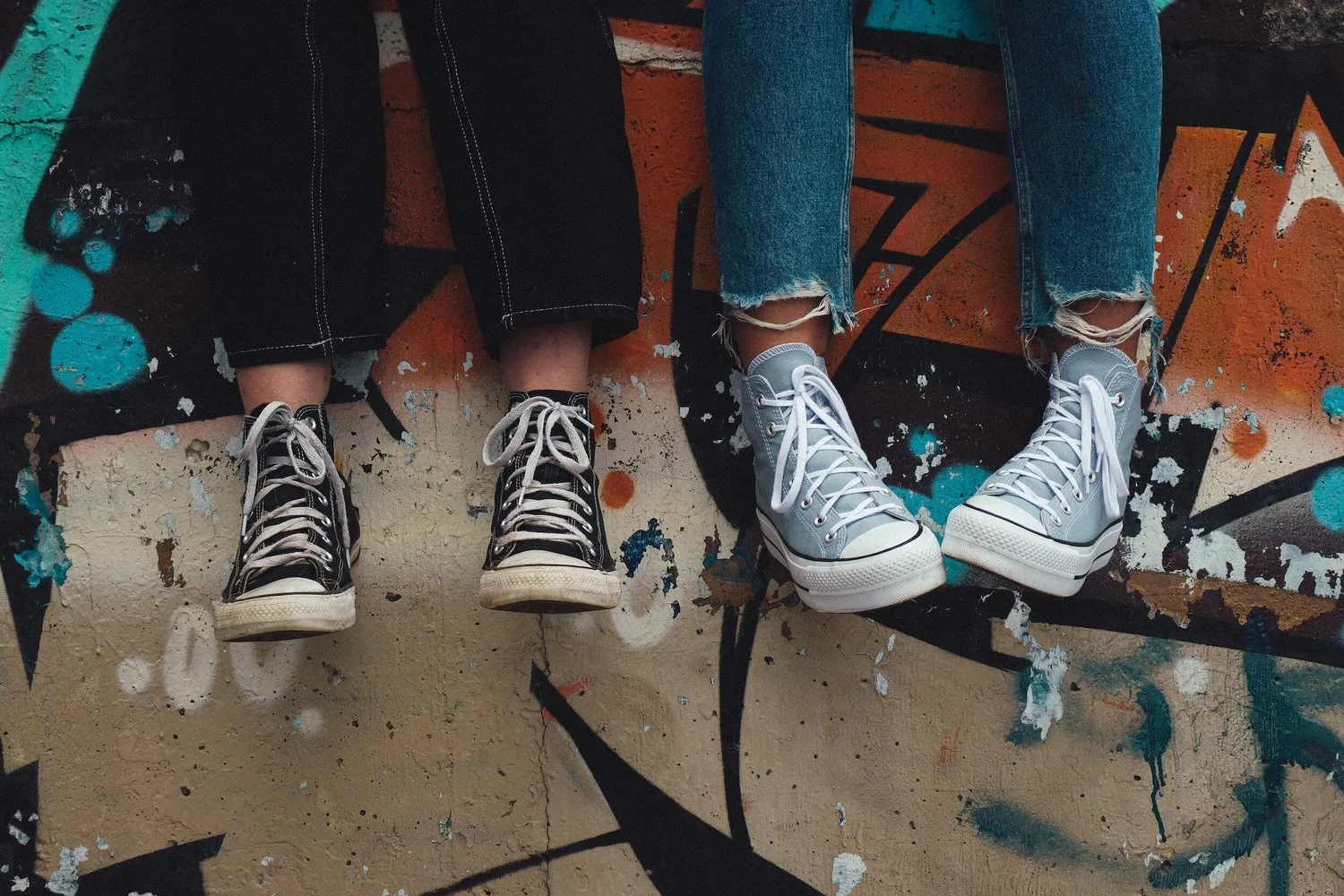 Close-up of teenagers’ sneakers as they sit side by side on a ledge