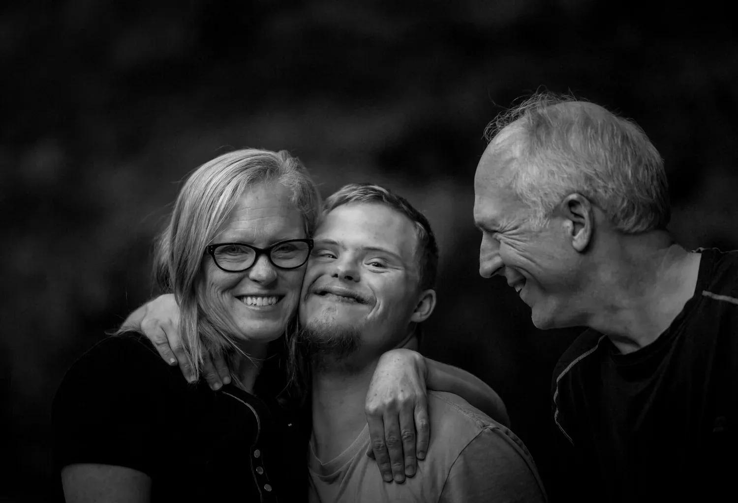 Black-and-white photo of a smiling family of three posing close together