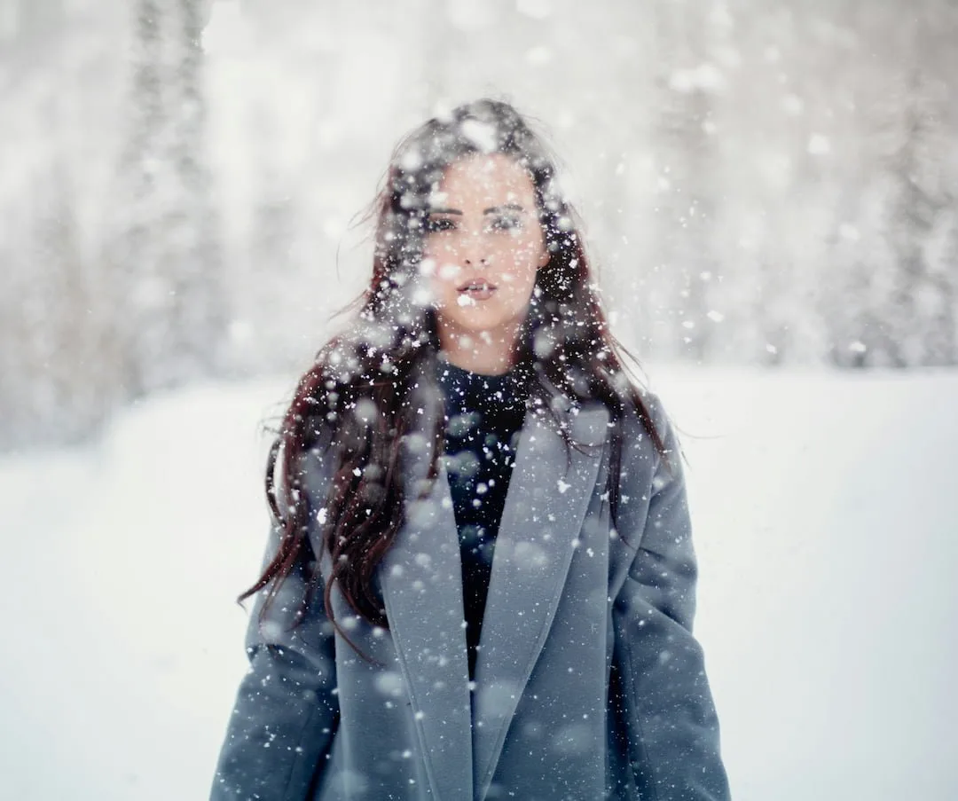 Woman in a gray coat standing still in falling snow