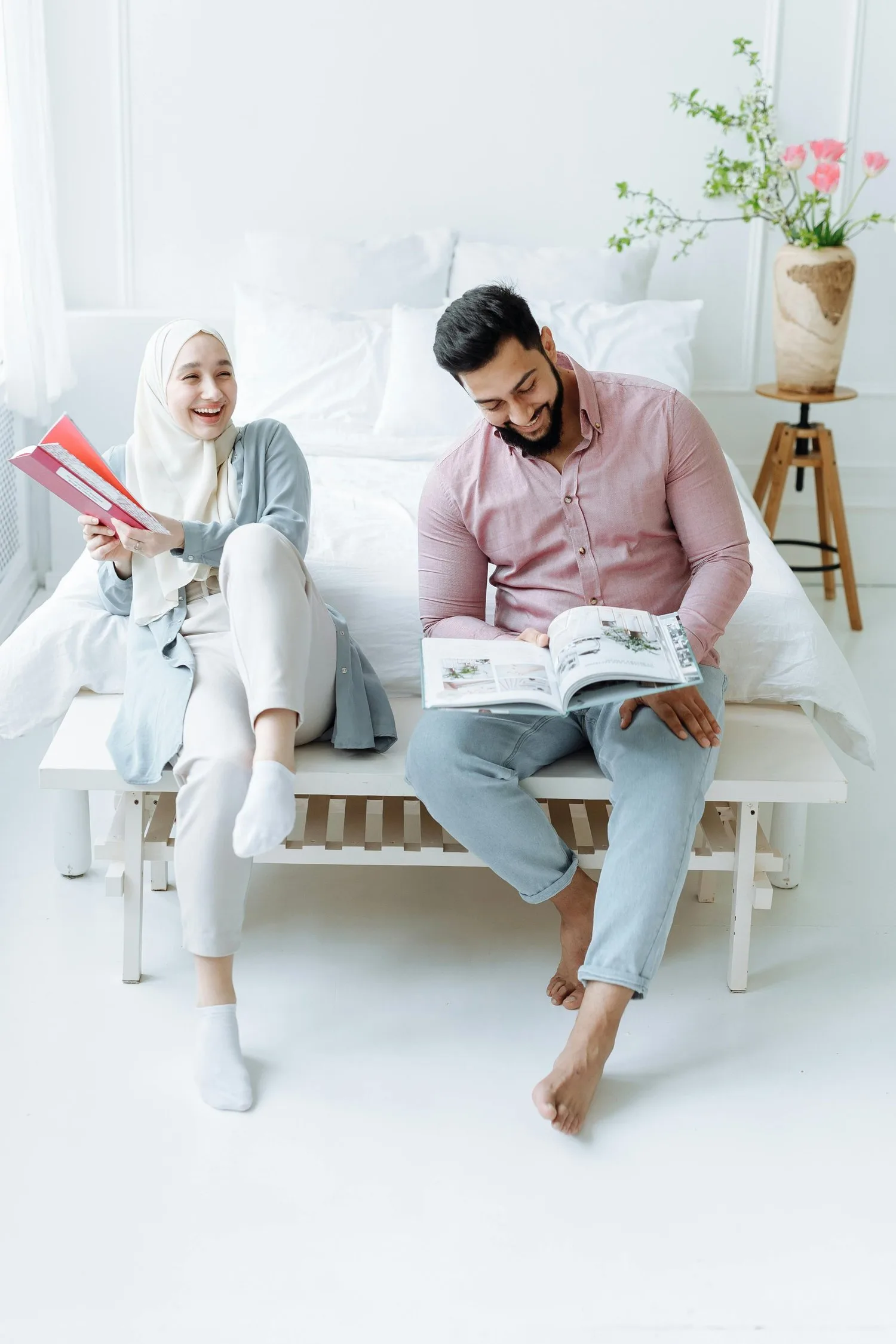 Couple relaxing on a white sofa, one reading a book