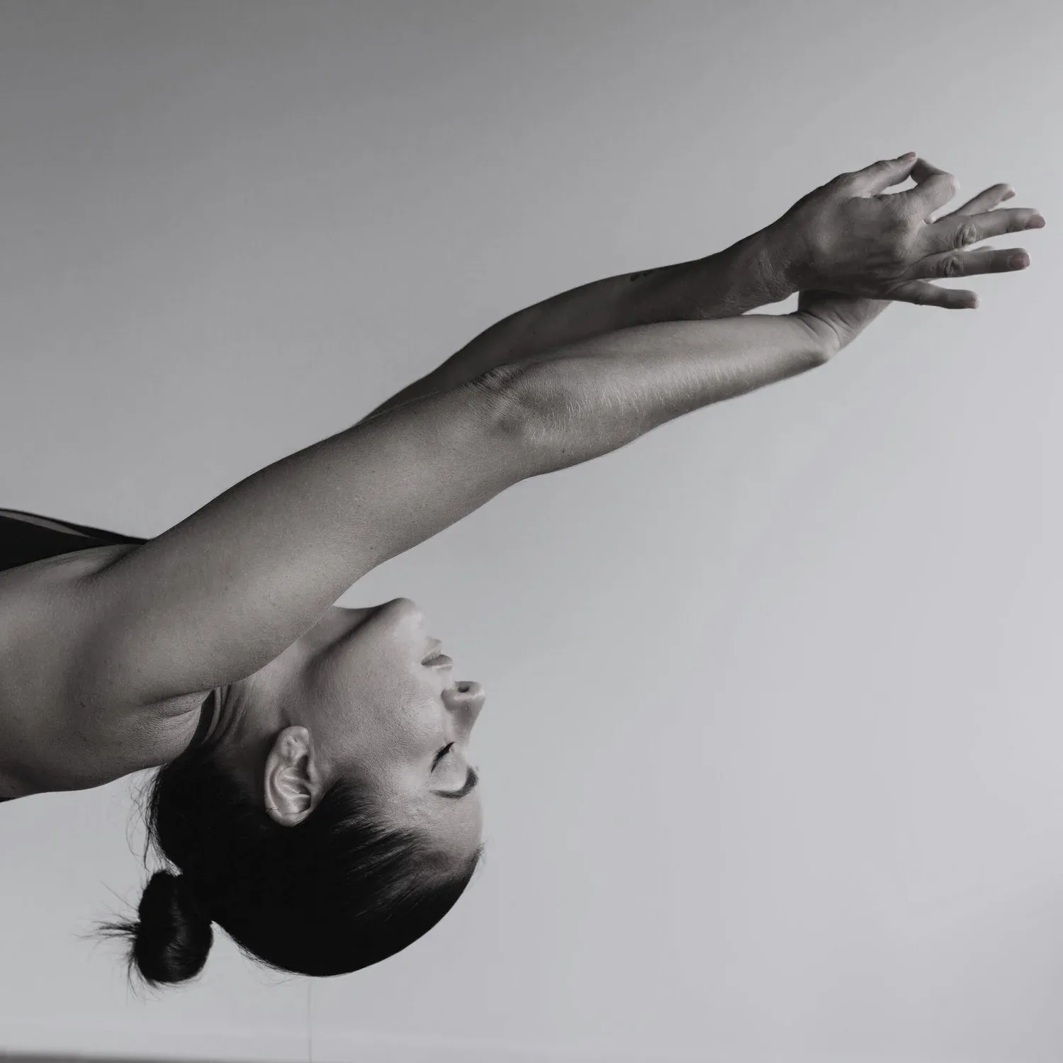 Black-and-white photo of a woman in a deep backbend with arms extended