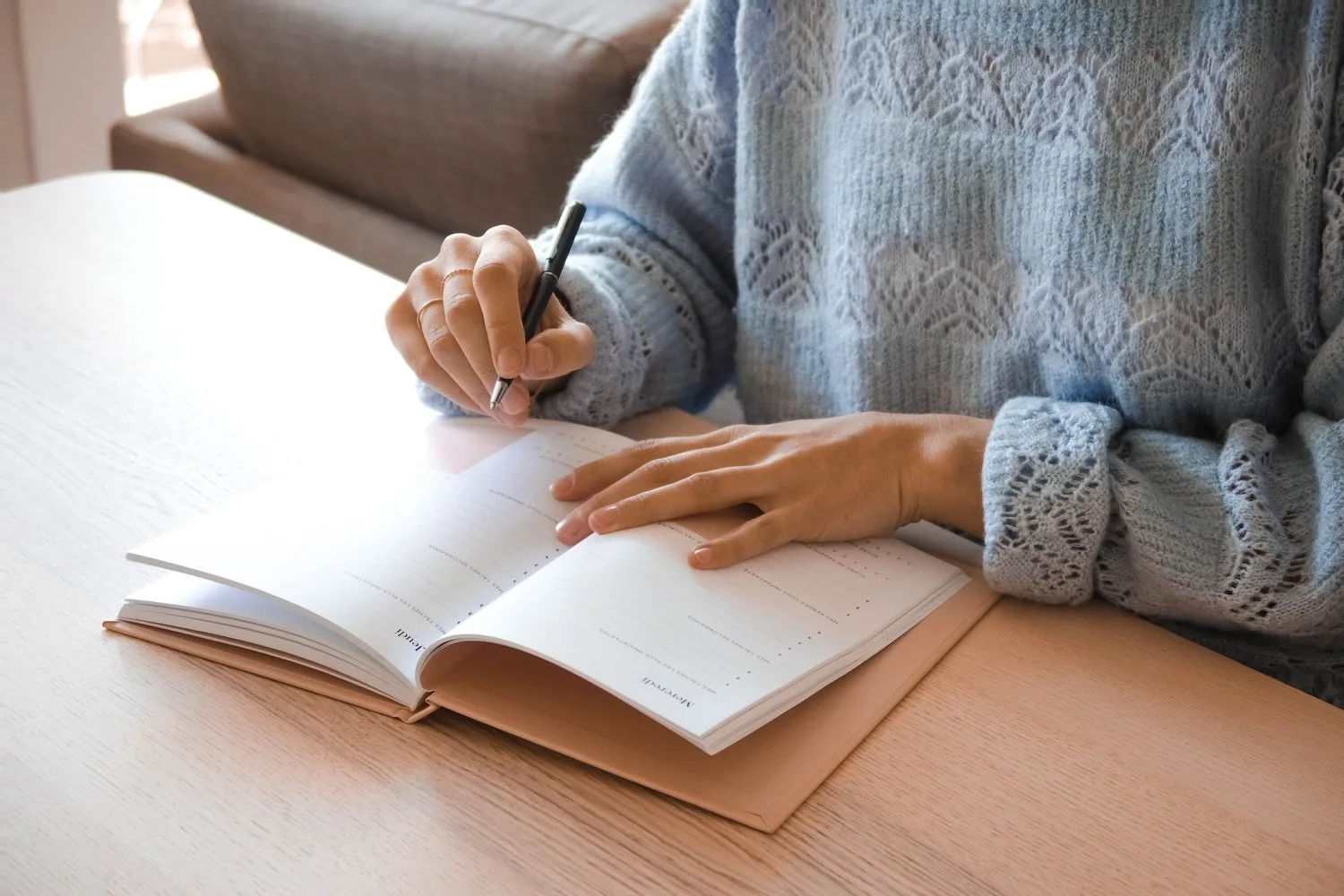 Hand writing in a notebook on a wooden desk