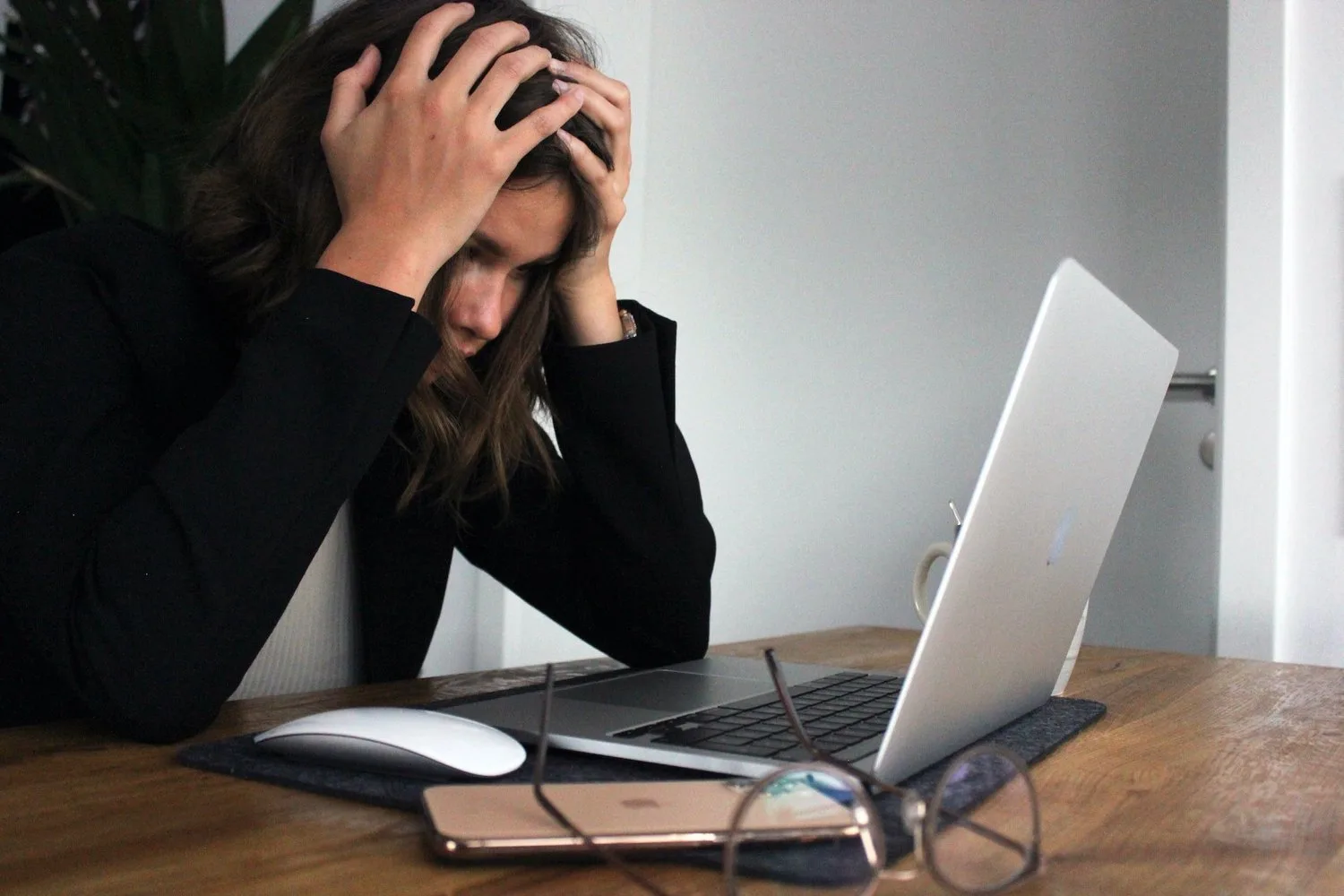 Stressed woman with her head in her hands at a laptop