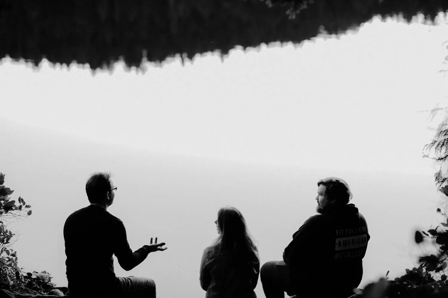 Silhouettes of three people talking in front of a bright sky