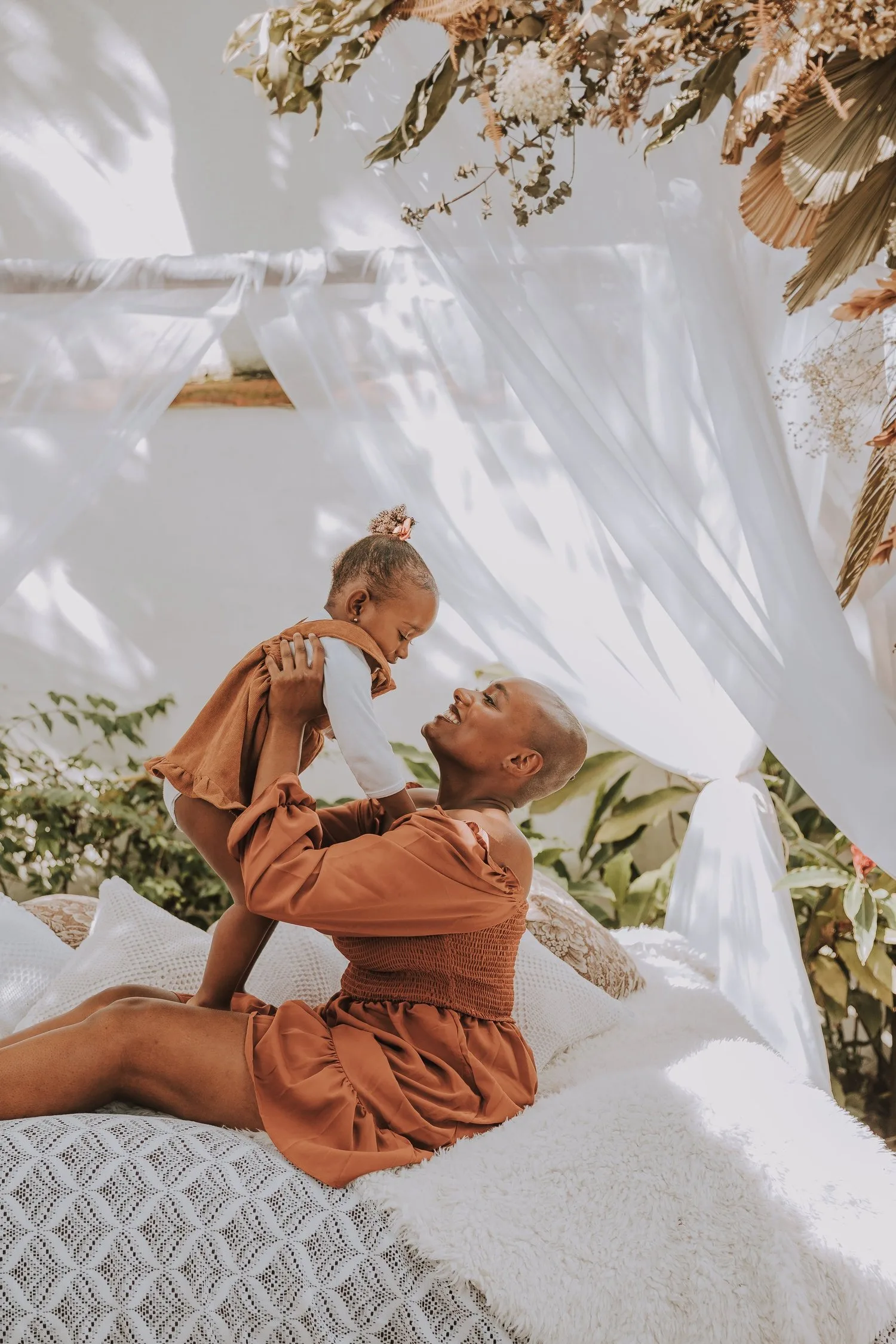 Two women relaxing on a bed with pillows, one resting against the other