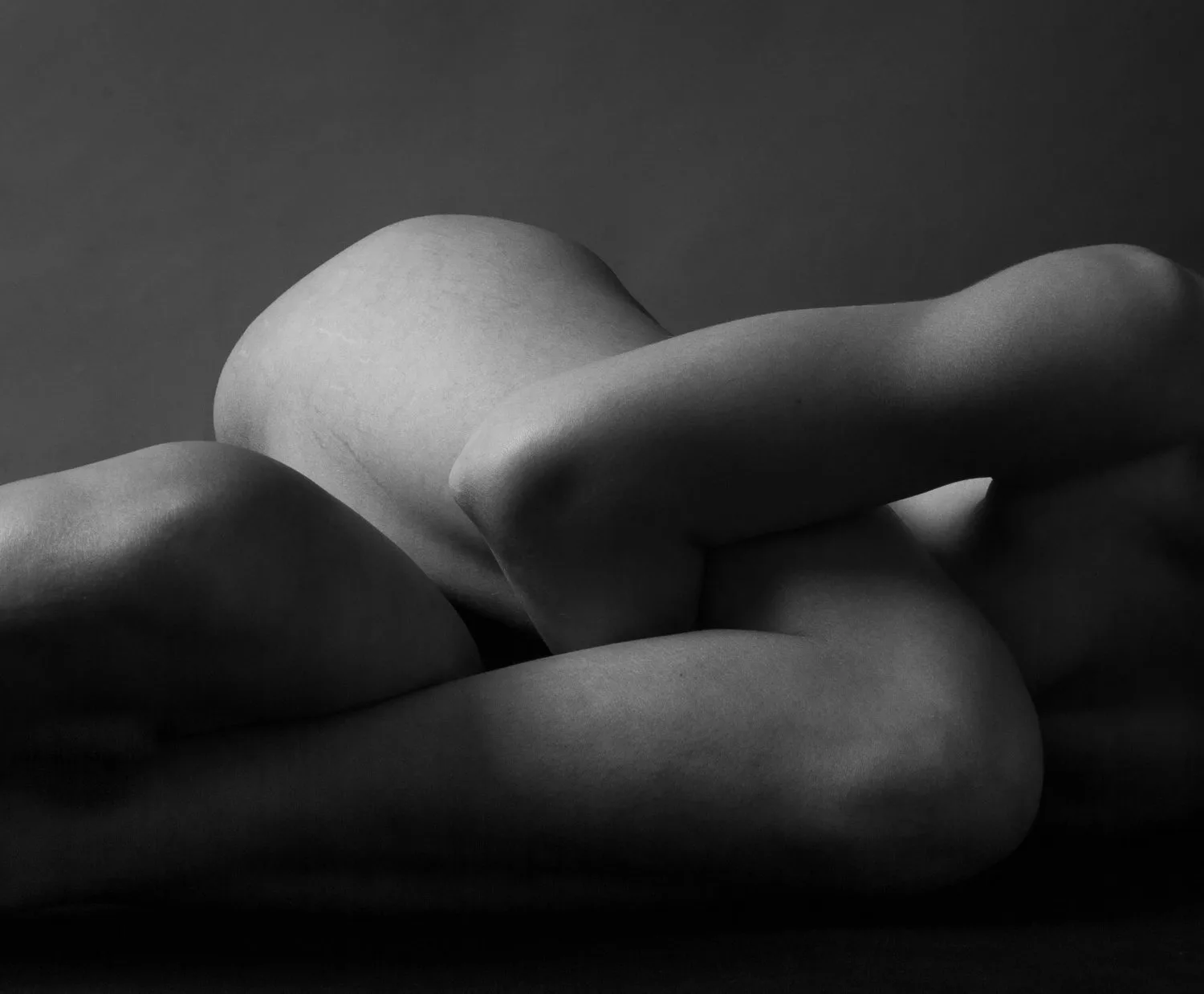 Black-and-white close-up of the curve of a person’s body in soft shadow
