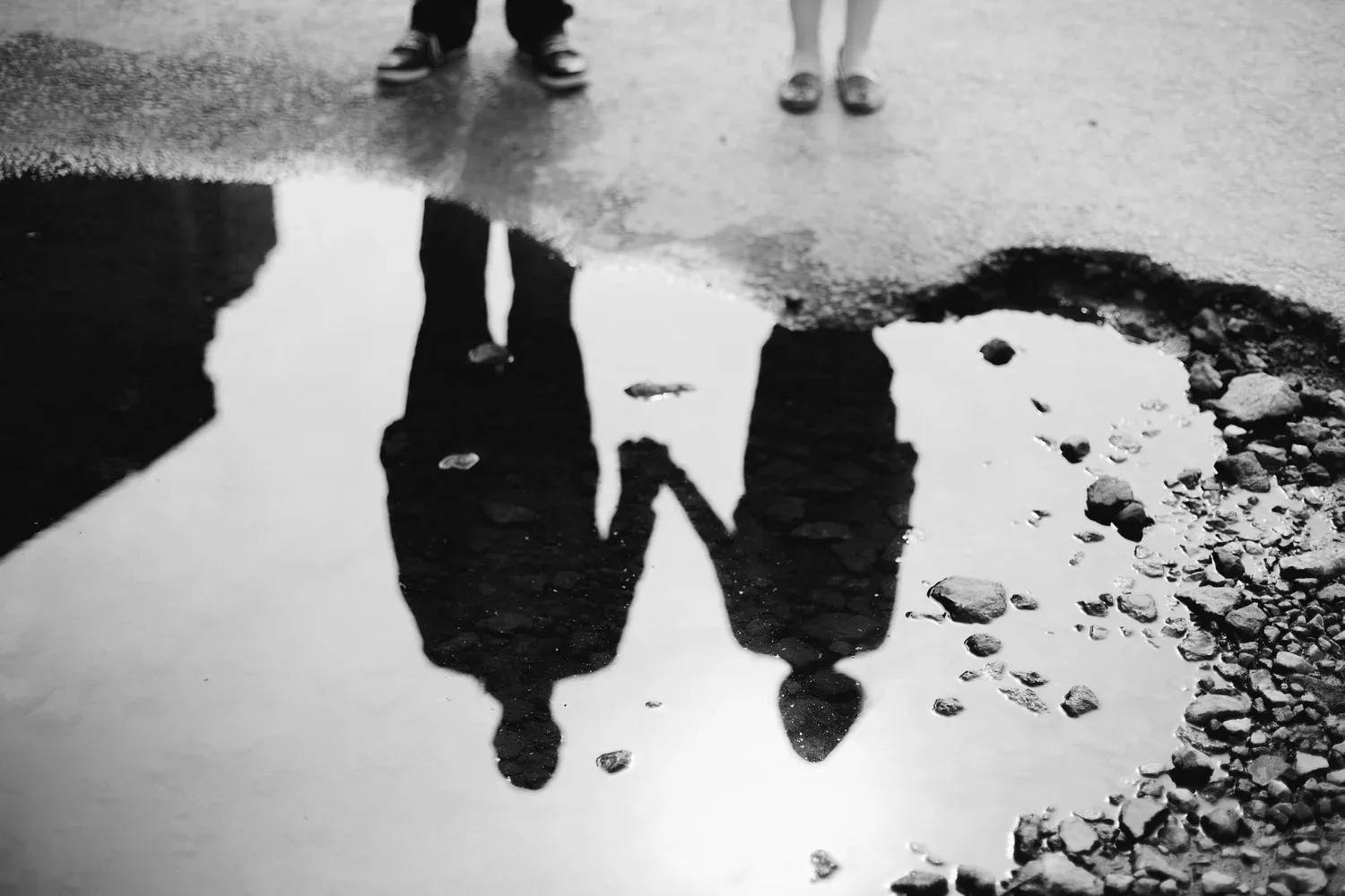 Reflection of two people holding hands in a puddle