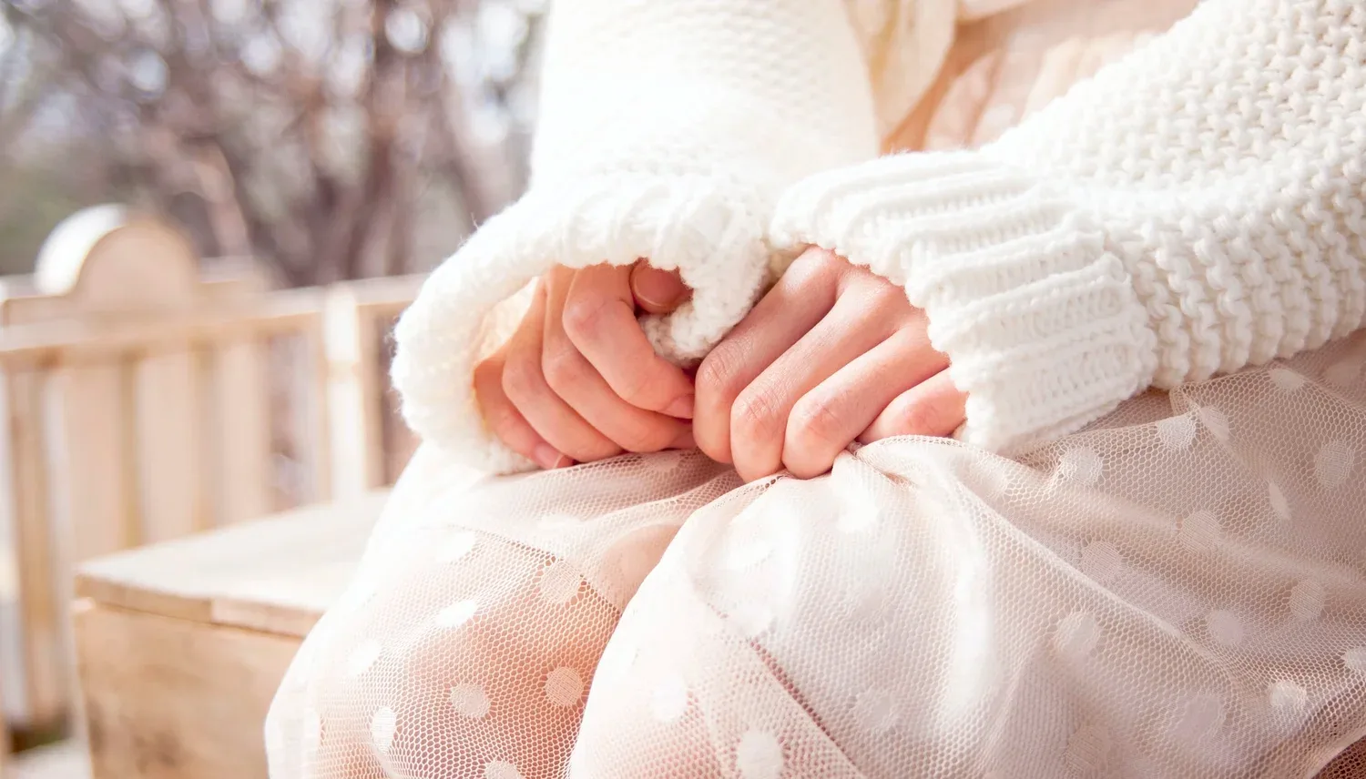 Close-up of hands in a cozy knit sweater resting in a lap