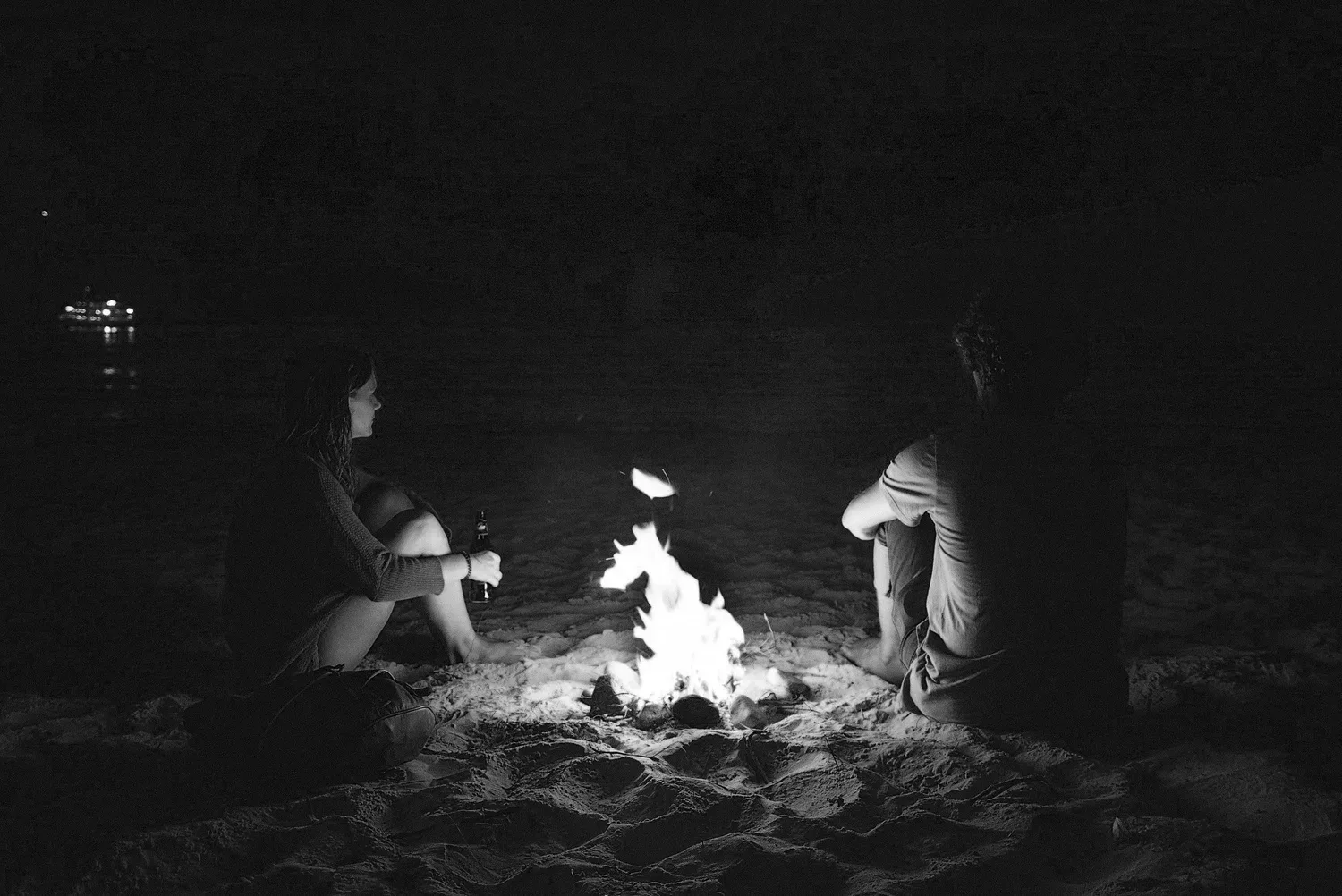 Black-and-white photo of people gathered around a campfire at night