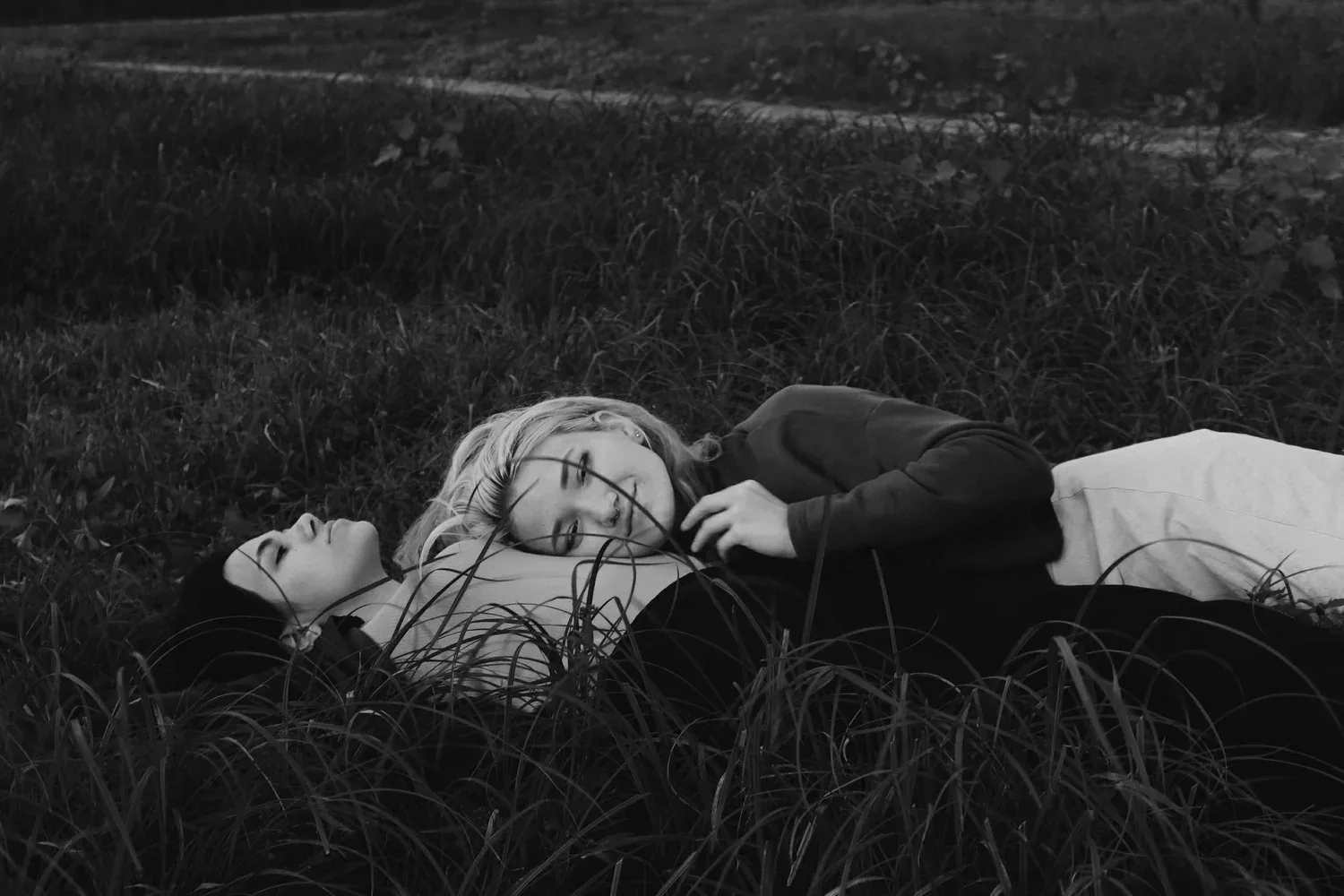 Black-and-white photo of a person lying on the grass with eyes closed