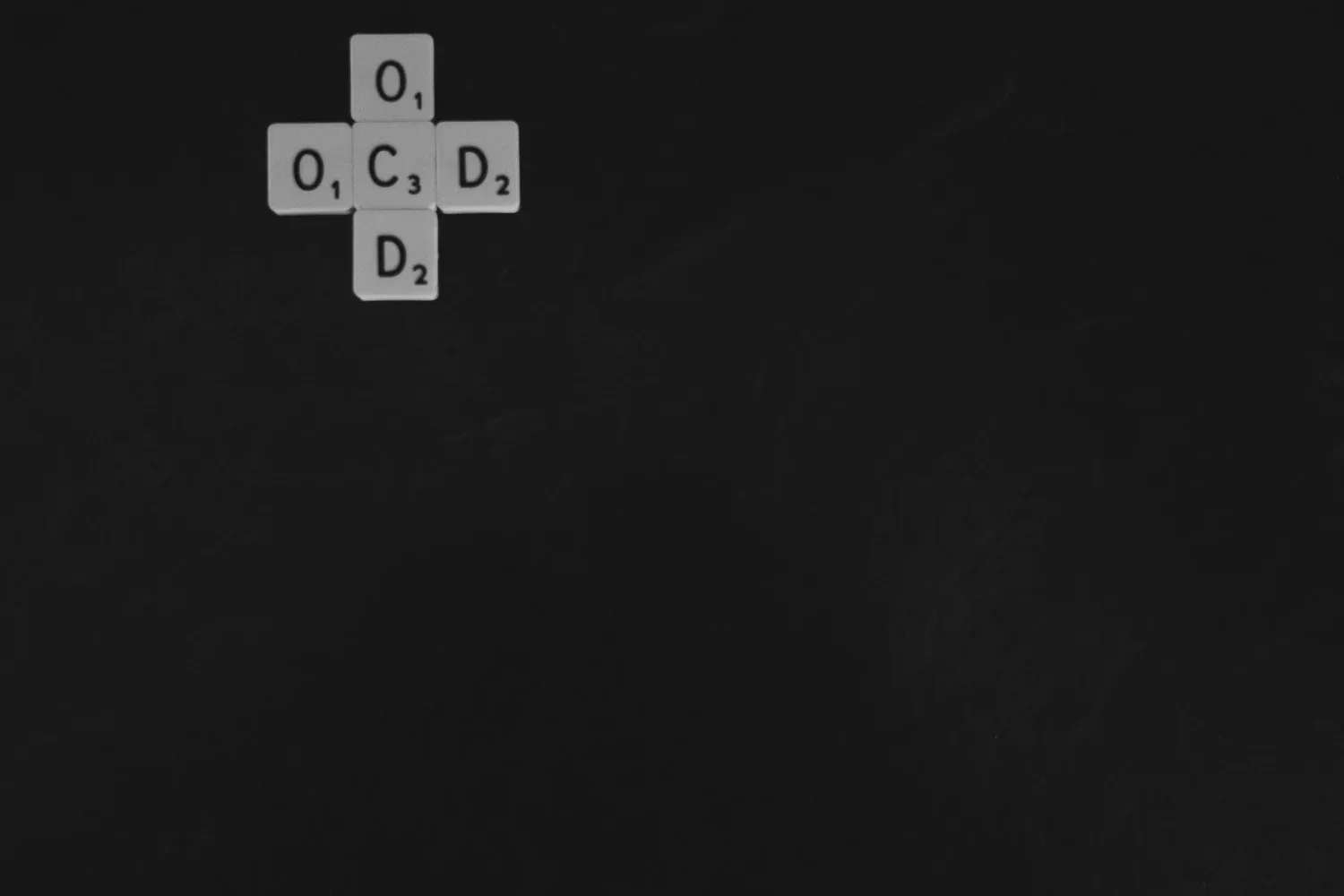 Letter tiles spelling OCD arranged in a cross on a black background