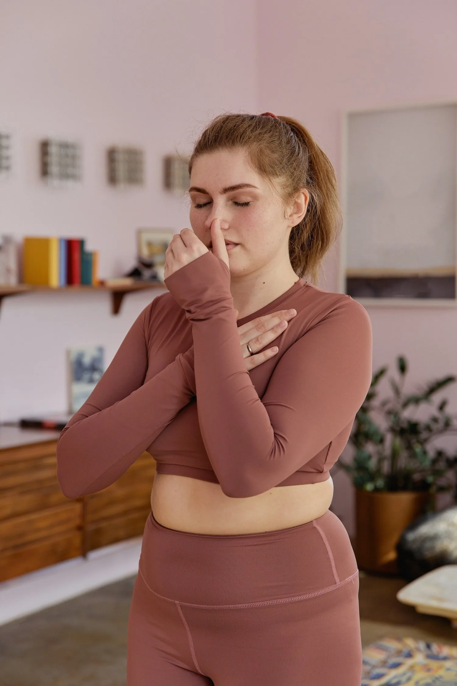 Woman in athletic wear with one hand on her chest, looking reflective