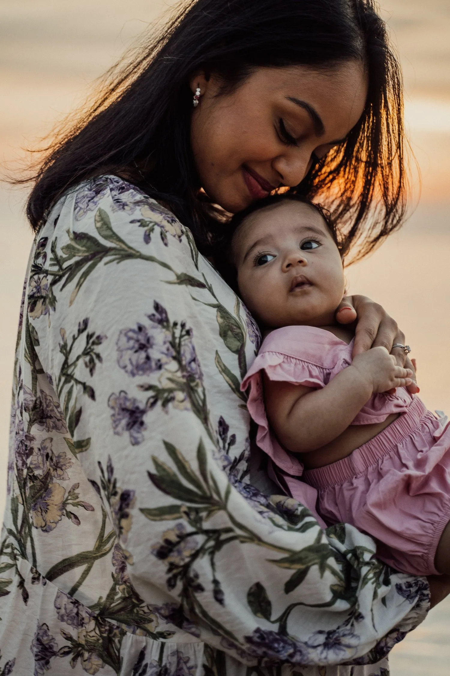 Mother in a floral robe cradling her infant against her cheek