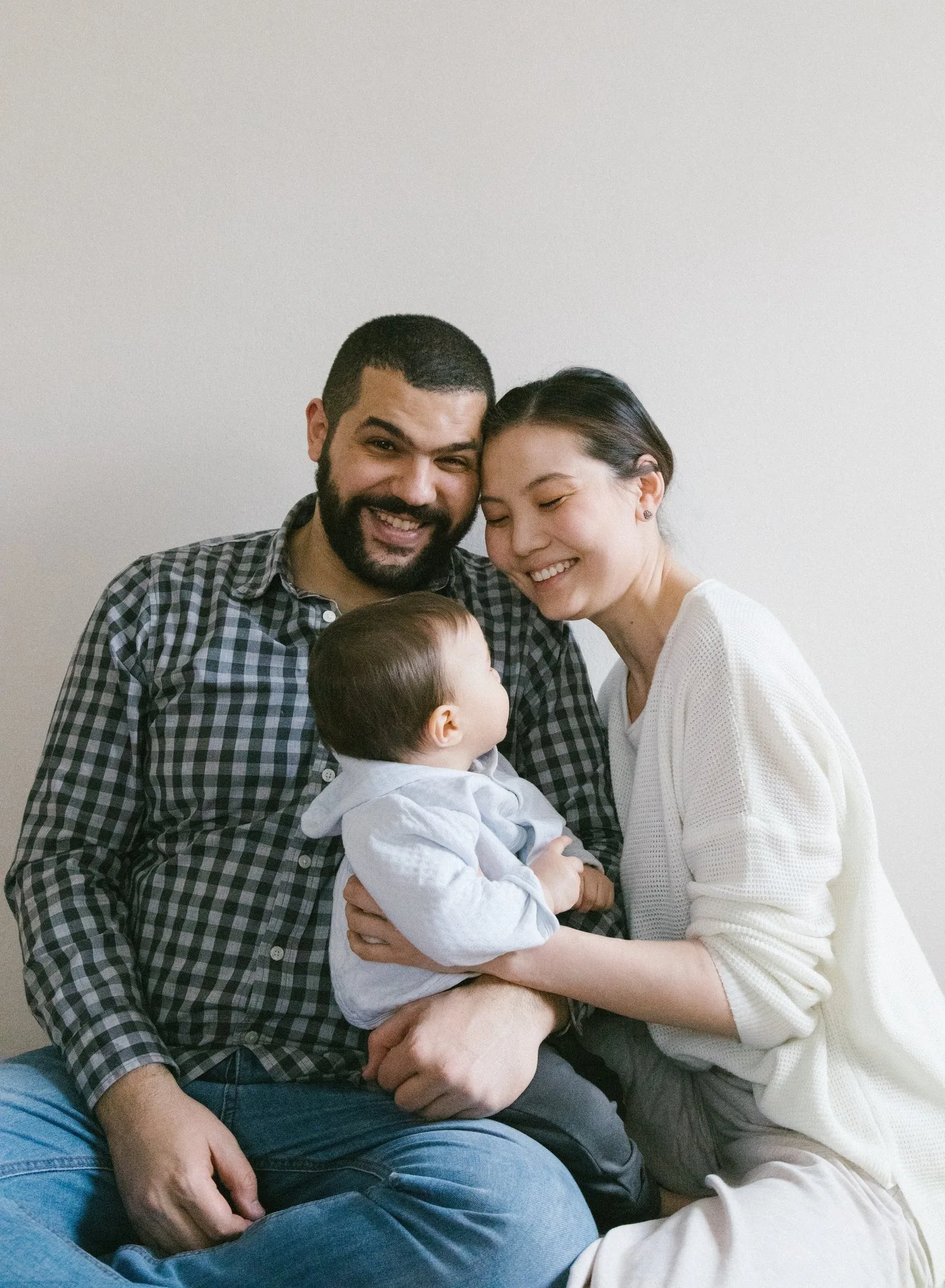 Parents sitting together holding their baby, smiling