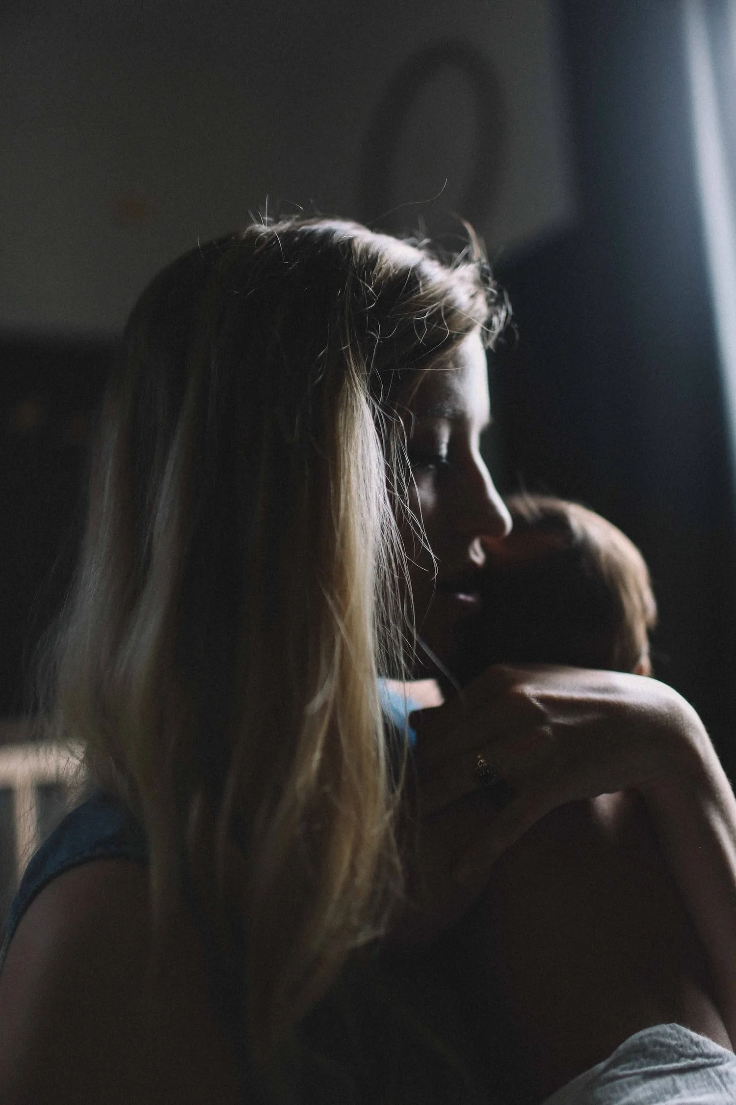 Mother holding her baby close in dim light