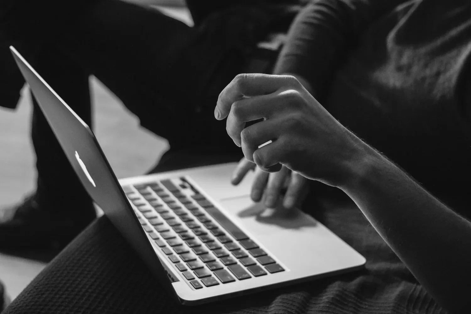 Black-and-white close-up of hands typing on a laptop