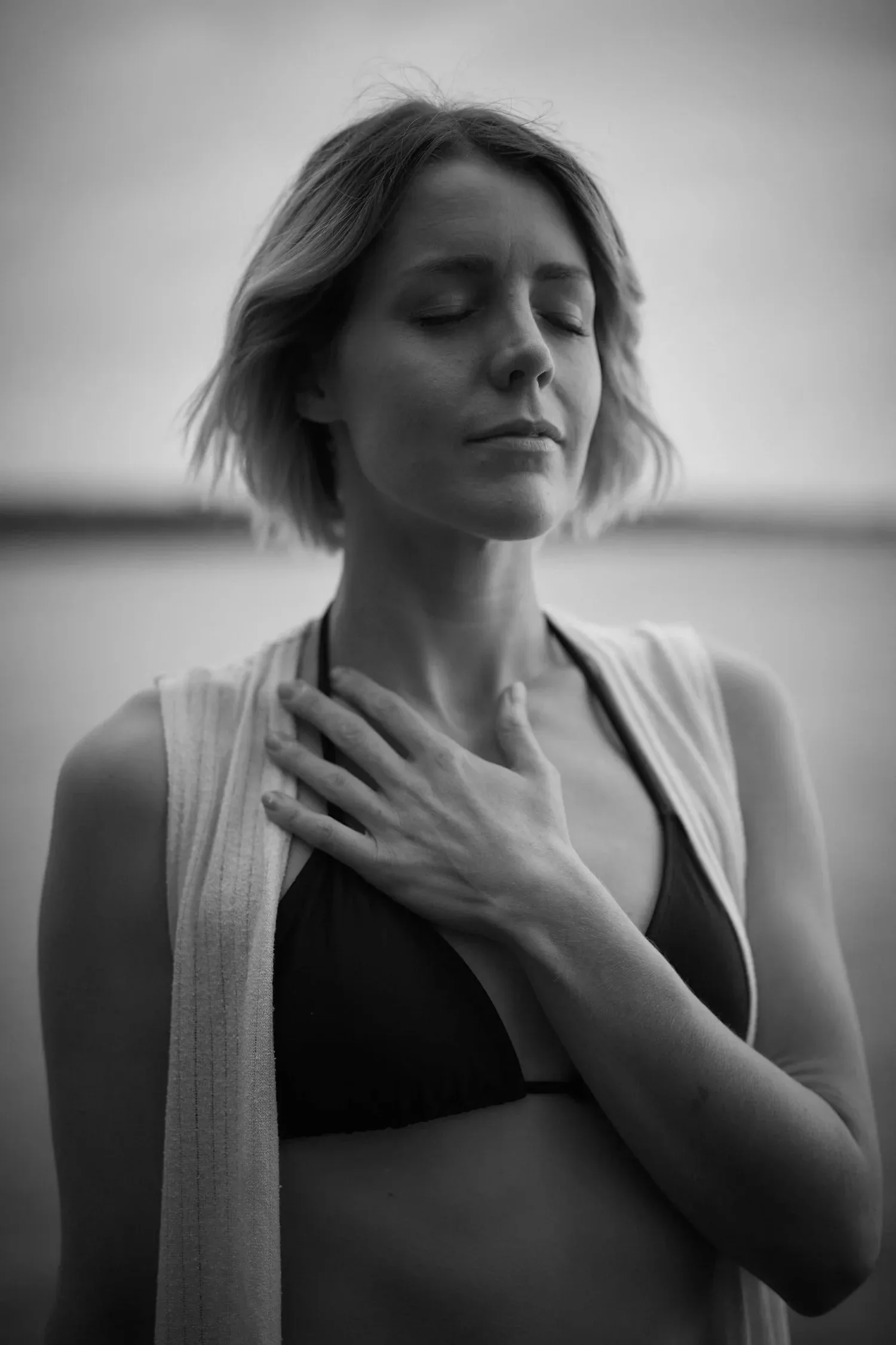 Black-and-white photo of a woman with eyes closed and hands on her chest