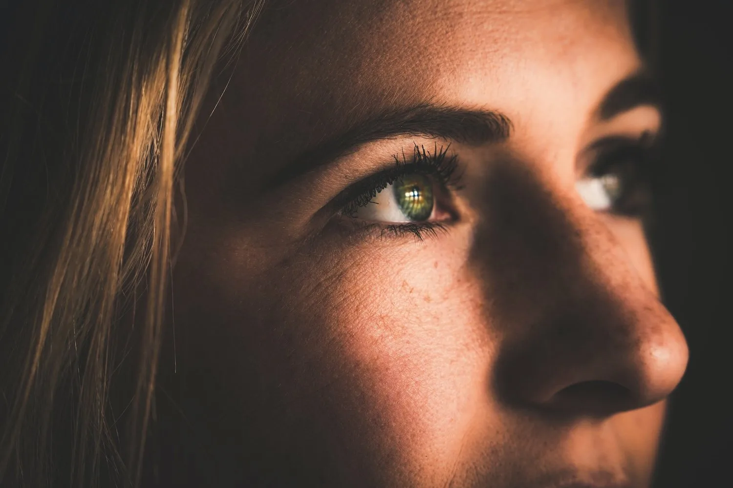 Close-up of a woman’s face in soft light, gazing into the distance