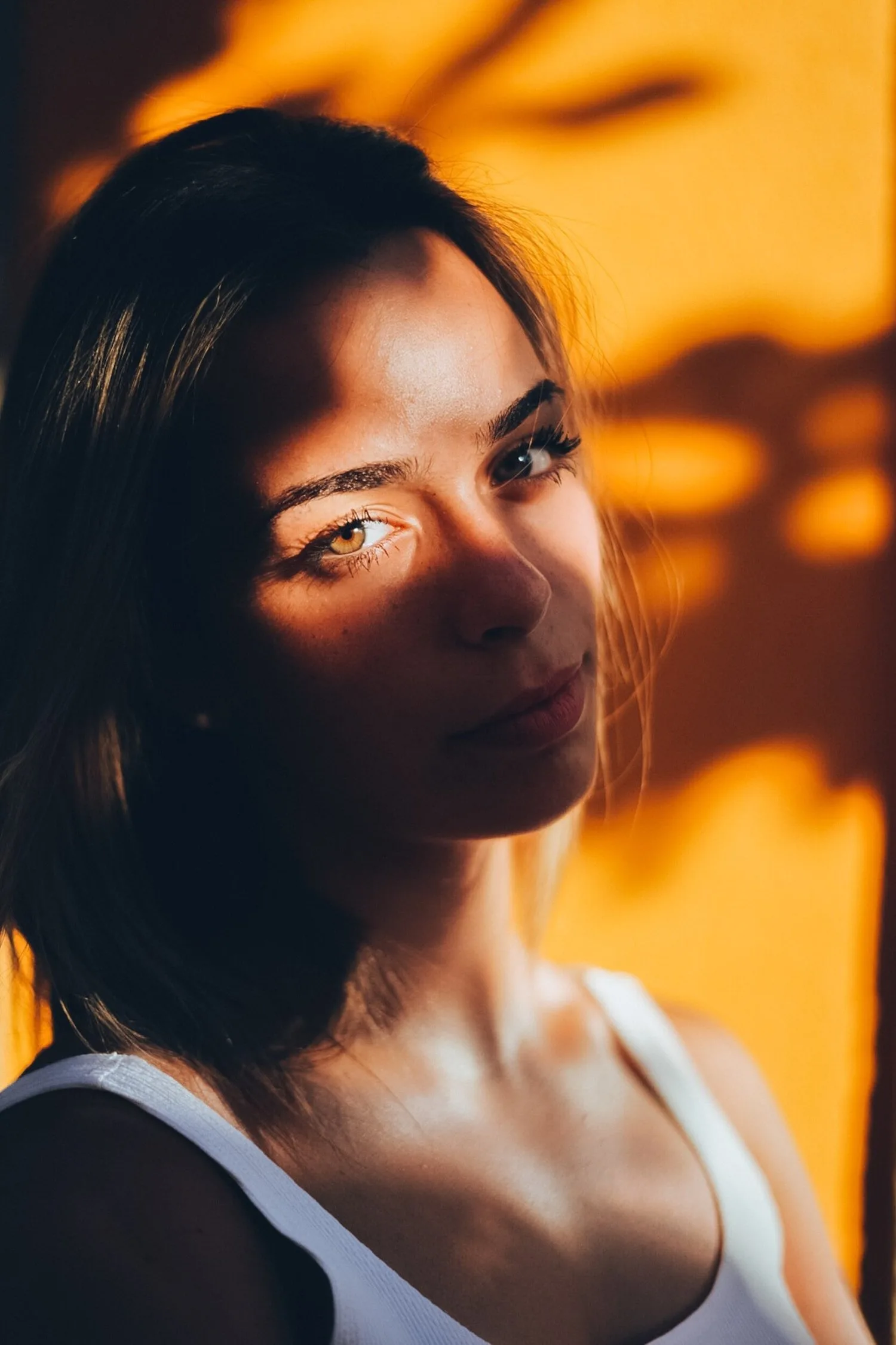 Woman in warm light with leaf shadows falling across her face