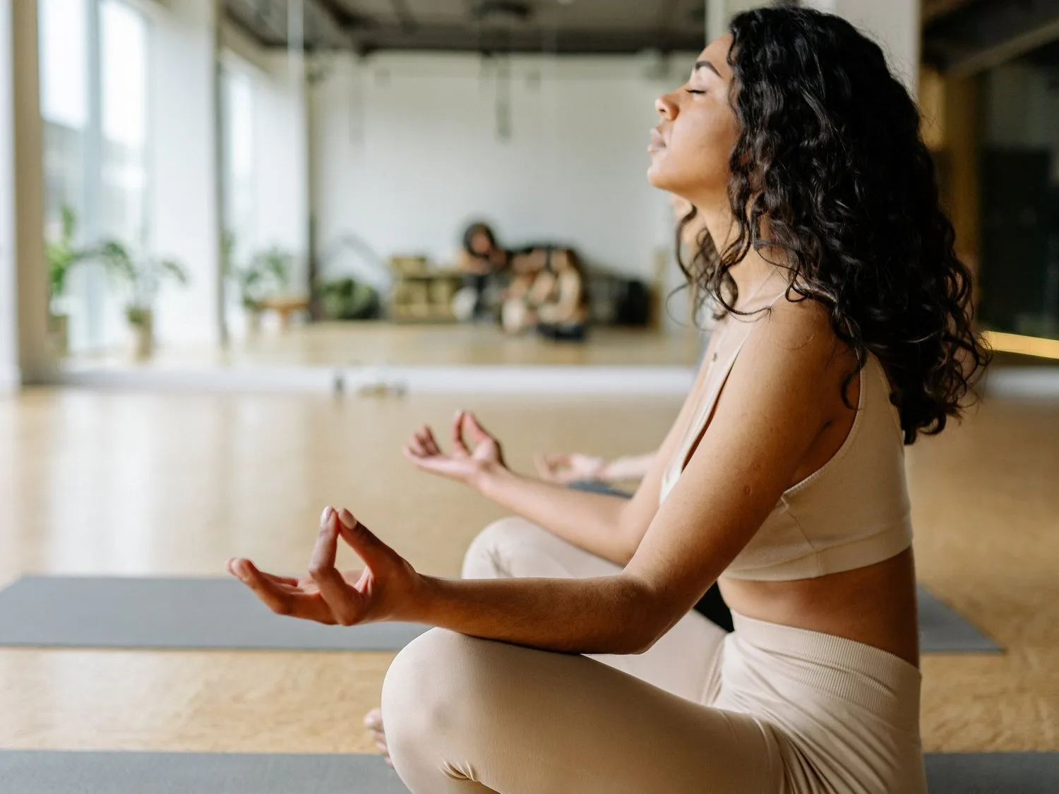 Woman meditating cross-legged on a mat in a spacious loft studio