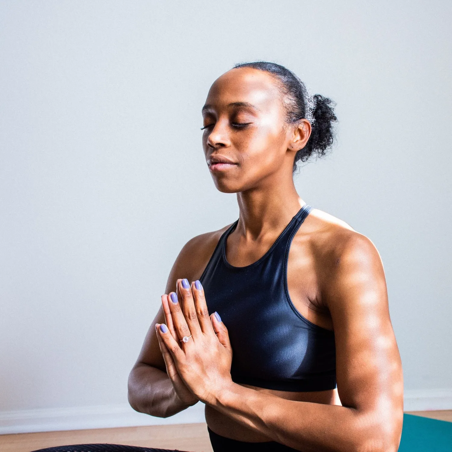 Woman with eyes closed and palms pressed together in a calm, meditative pose