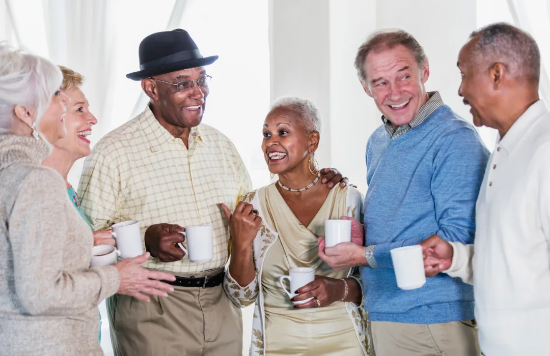 Group of older adults chatting and laughing together over coffee