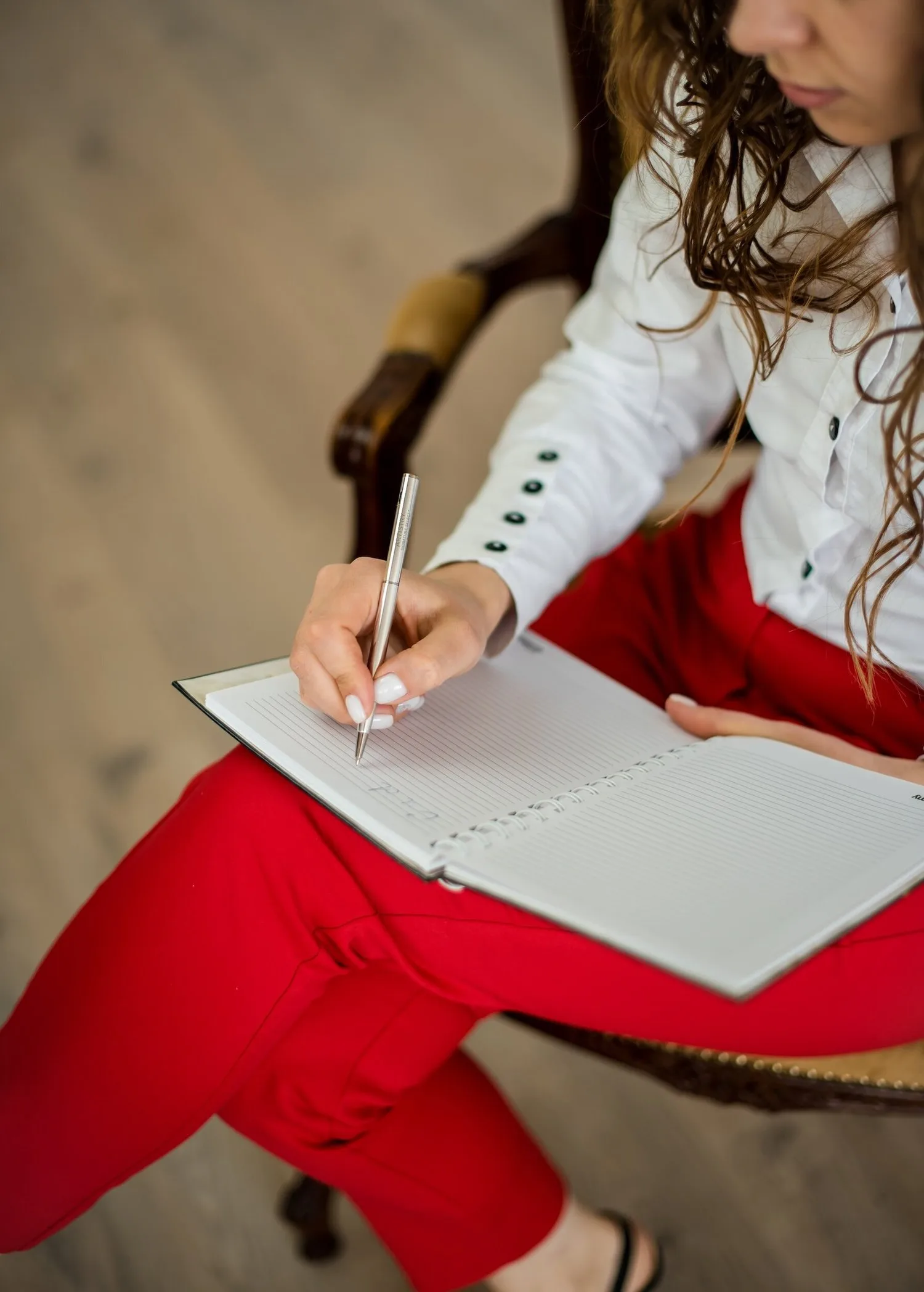 Woman in red pants sitting and writing in a notebook