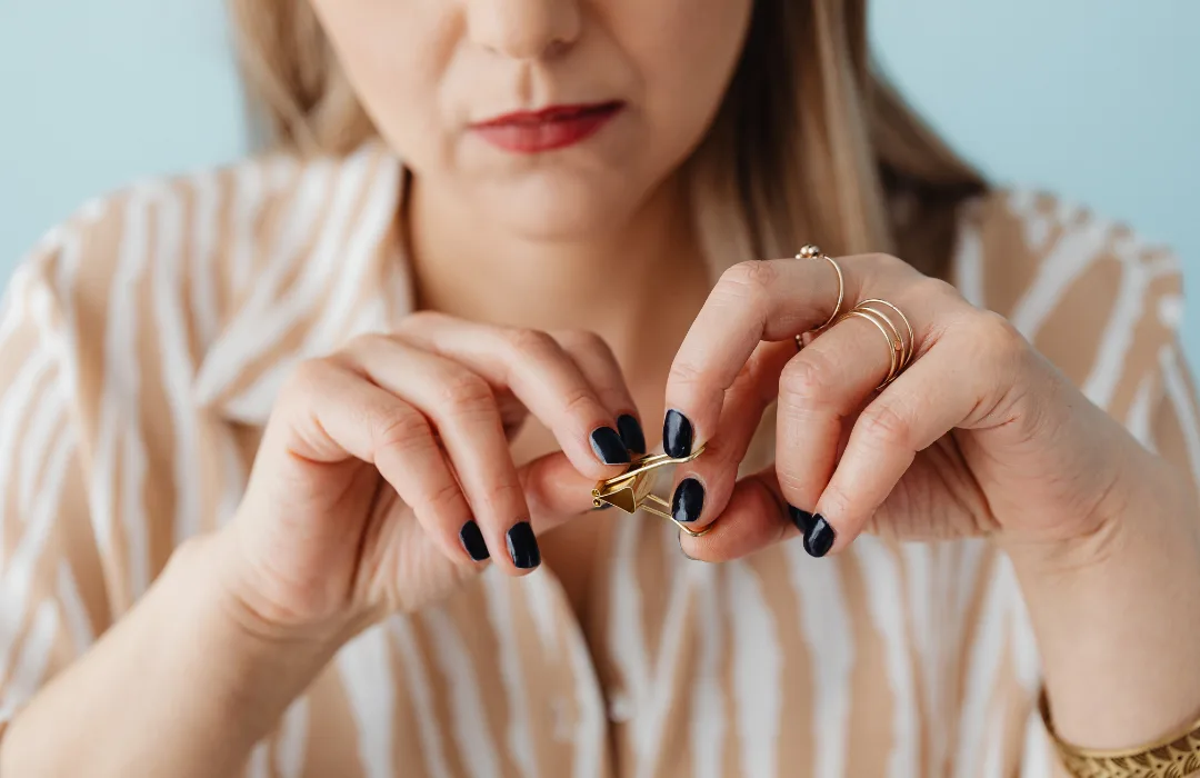 Woman in a striped shirt holding a small pill between her fingers
