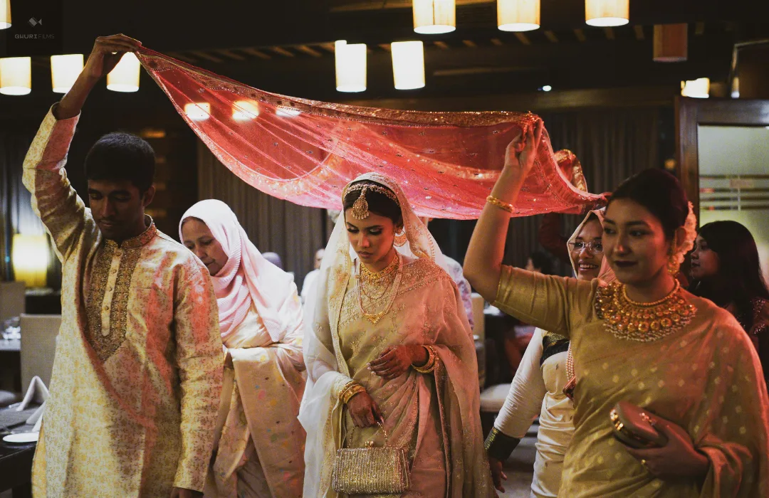 Women in colorful saris celebrating together under a red canopy at a South Asian gathering