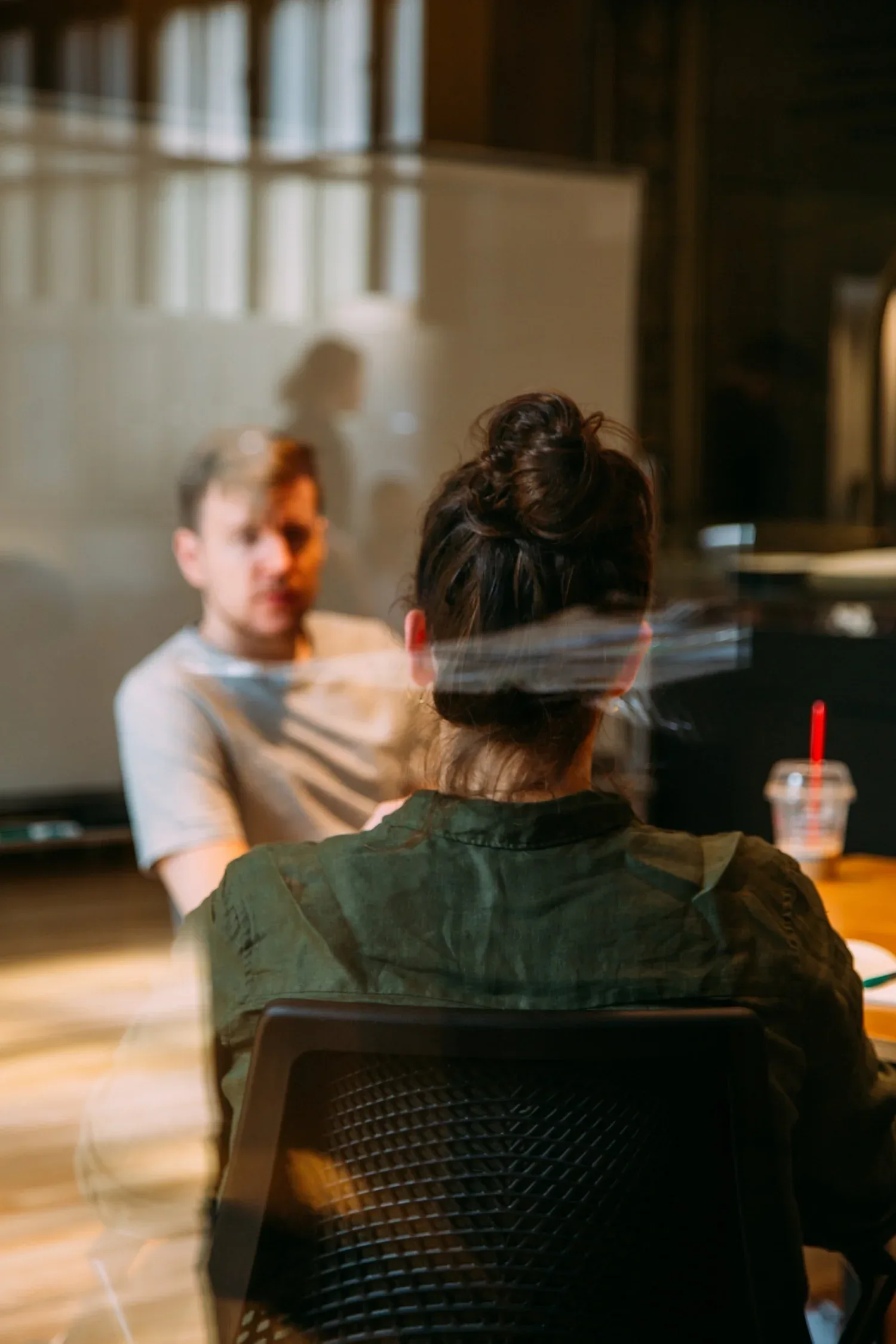 Two people talking across a table, seen through a window