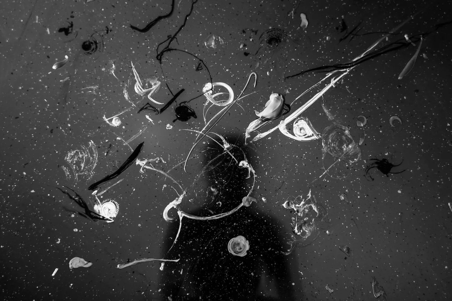Black-and-white overhead view of a person lying on the ground surrounded by scattered objects