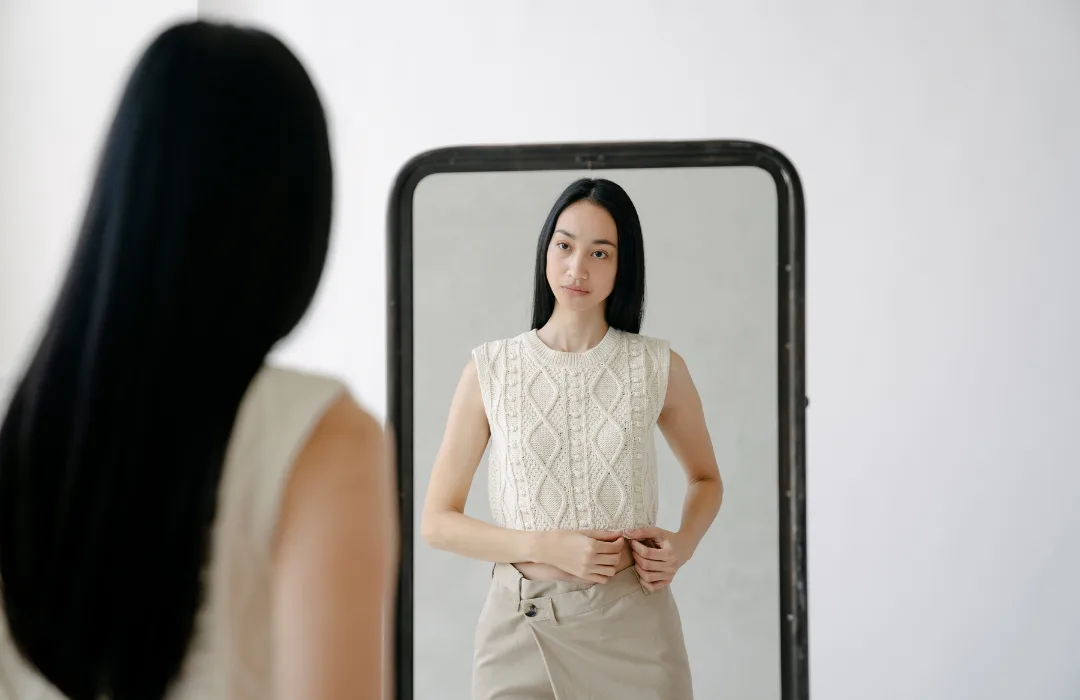 Woman looking at her reflection in a full-length mirror