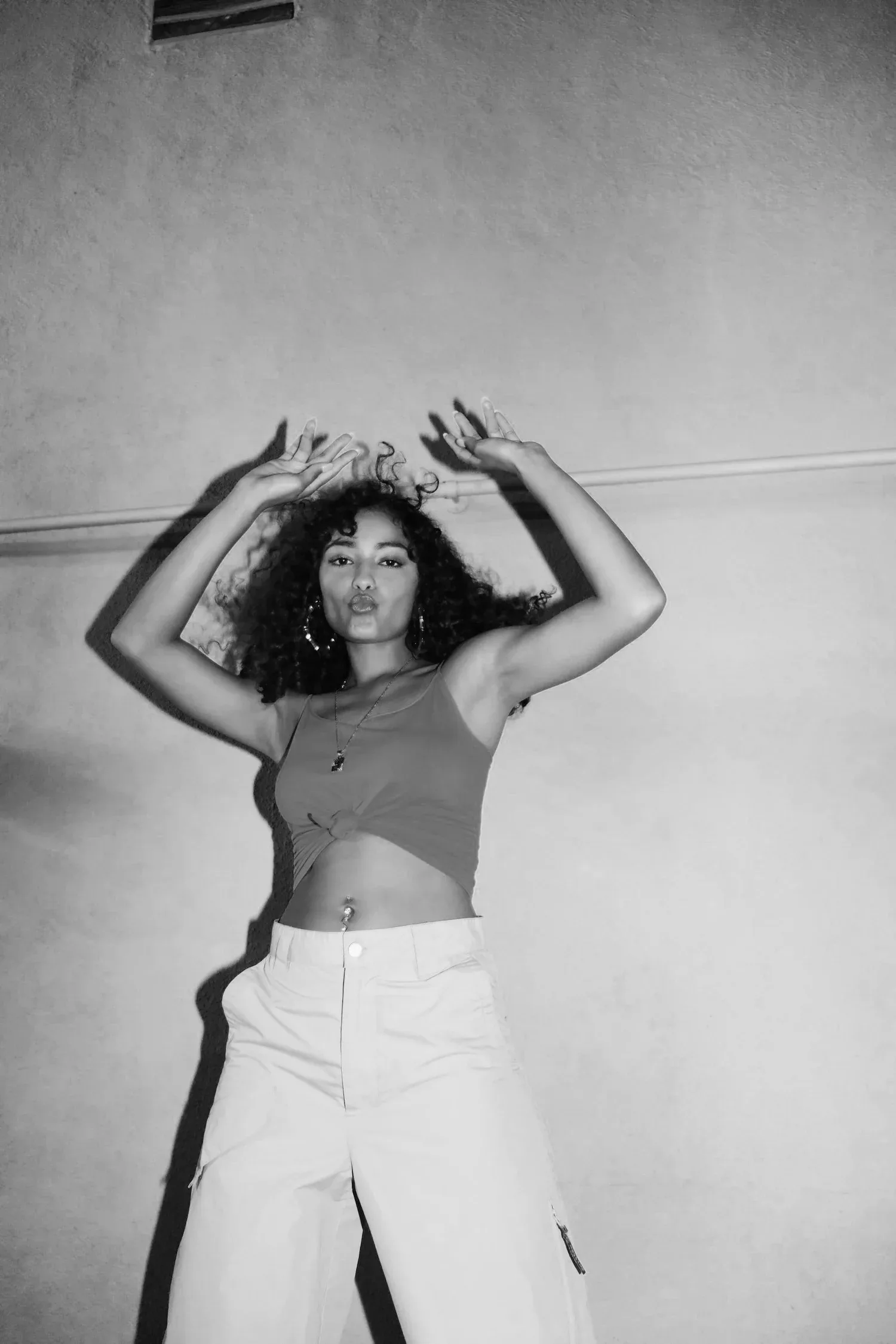 Black-and-white photo of a woman posing with arms framing her head
