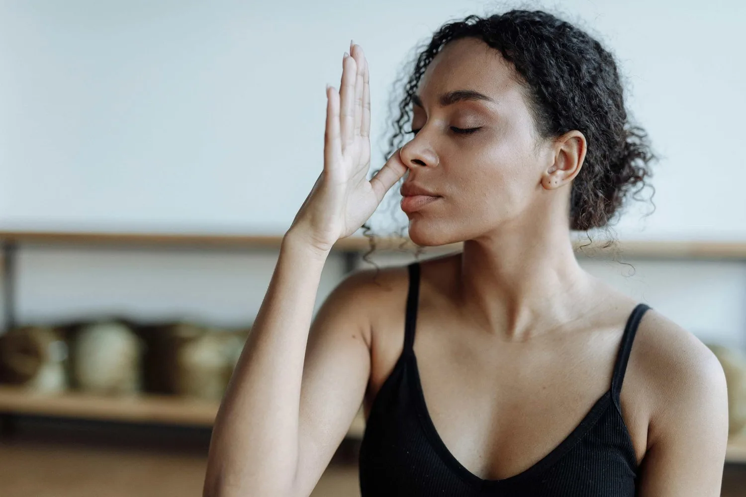 Woman with eyes closed holding one hand beside her face in a calming gesture
