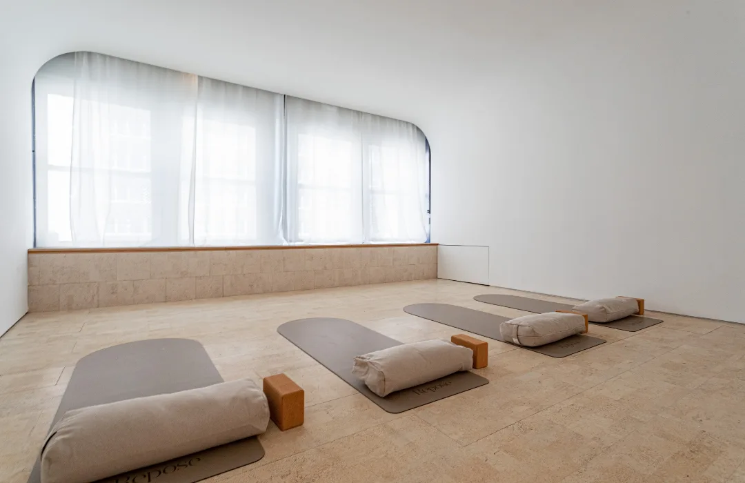 Empty studio with floor cushions and bolsters arranged beneath arched windows