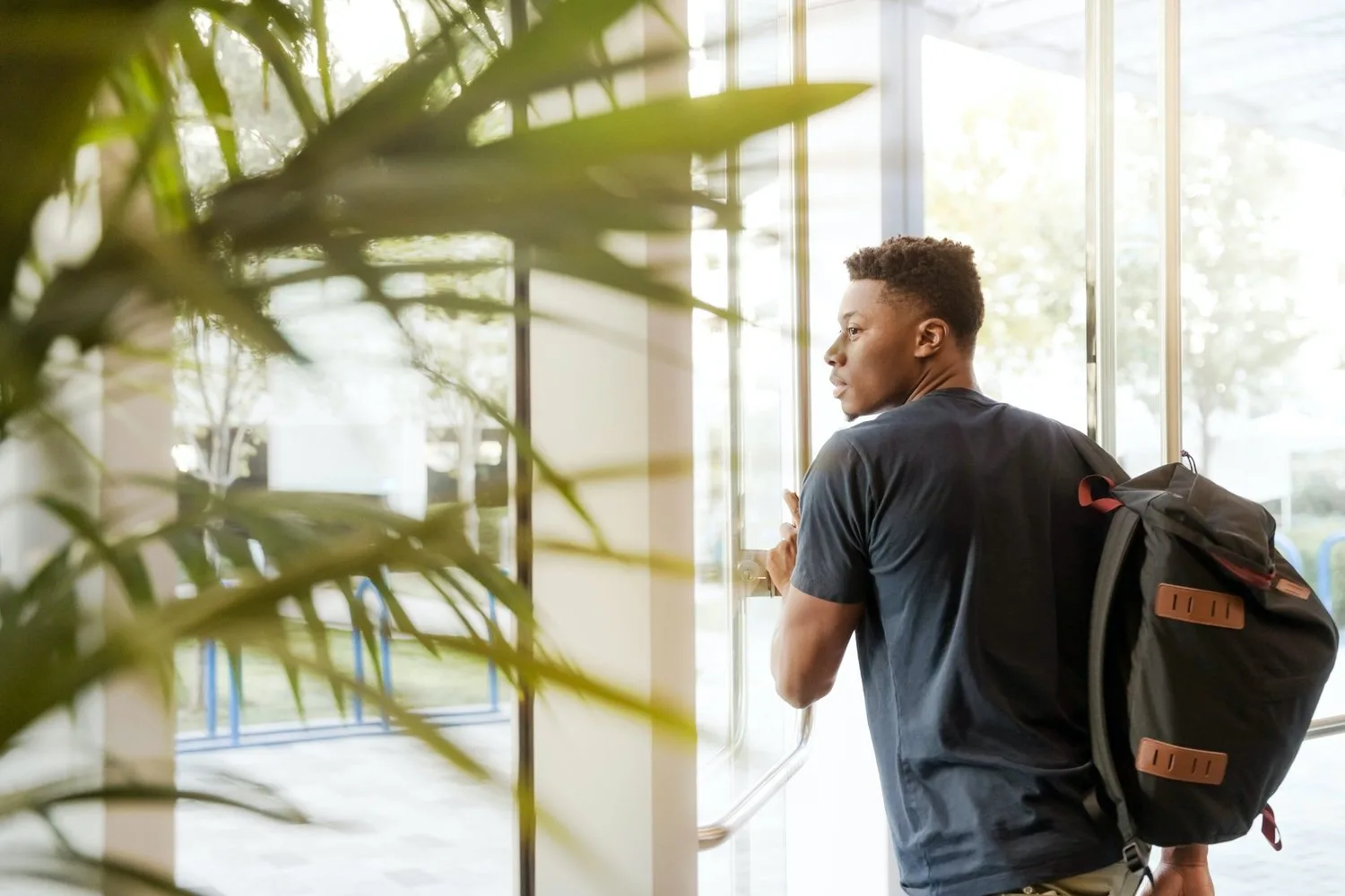 Young man with a backpack standing in a bright hallway