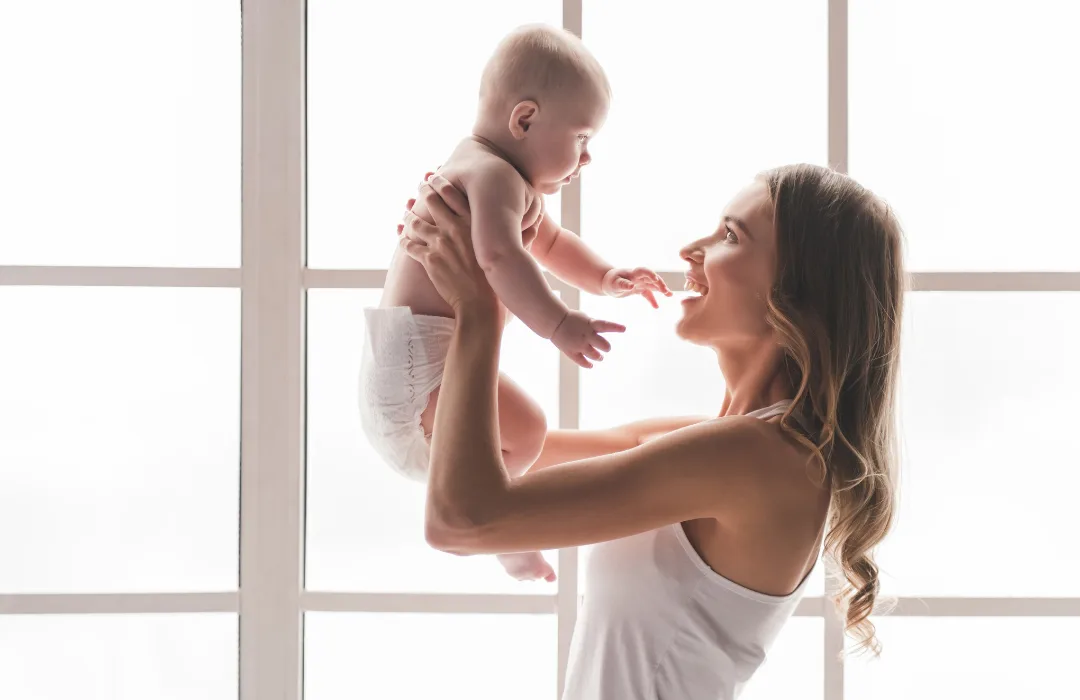 Mother lifting her baby toward a bright window