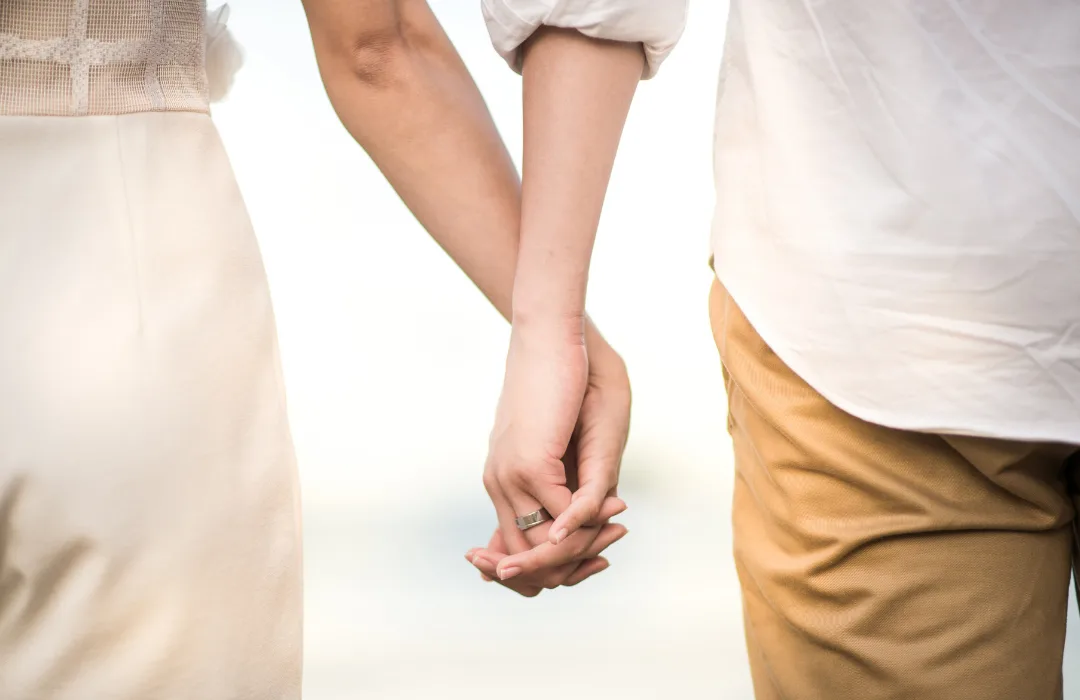 Two people holding hands, shown from the waist down in soft light