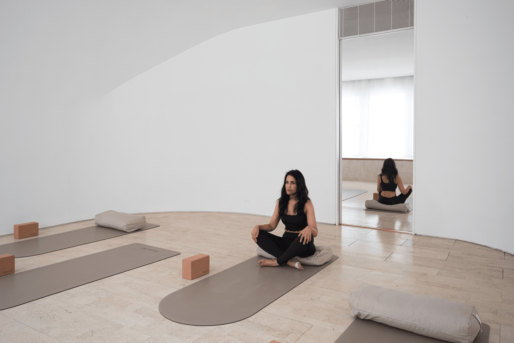 A person seated in meditation in a calm, light-filled studio